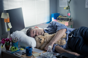 Office worker sleeping at work with teddy bear