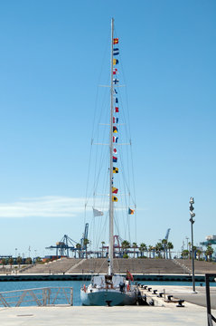 Yacht with Morse code flags on mast moored to the pear