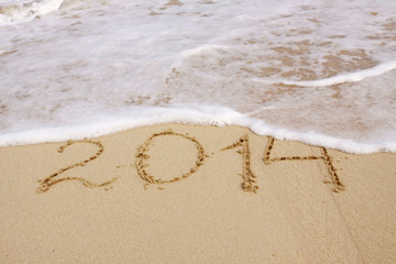 Year 2014 hand written on the  sand.