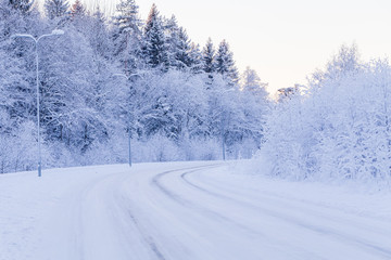 Winter evening forest with road covered with snow