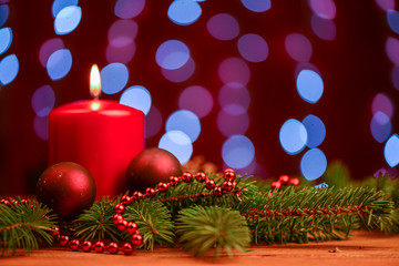 Red candle and ornament  on pine branch on table