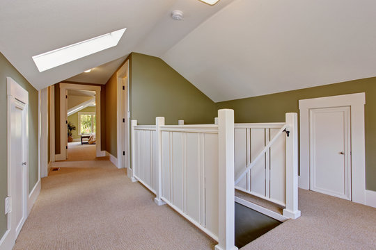 Green and white upstairs hallway with vaulted ceiling and skylig