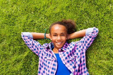 Smiling beautiful African girl laying on grass