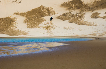 Hiker climbing up a sand dune