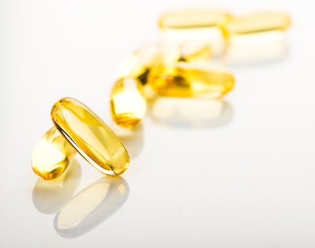 shiny yellow vitamin e fish oil capsule on white background