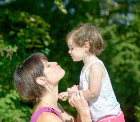 a beautiful mom is a hug to her daughter in nature