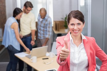 Happy businesswoman smiling at camera giving thumbs up