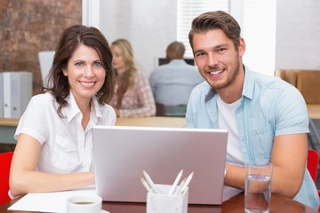 Smiling business people working together with laptop