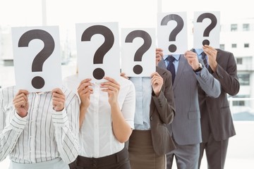 Business people holding question mark signs in office
