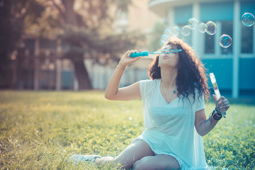 young beautiful moroccan curly woman blowing bubbles