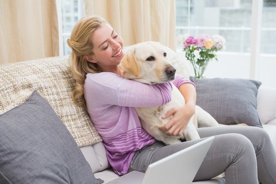 Beautiful blonde relaxing on the couch with pet dog