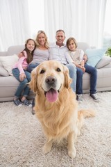 Family sitting on the couch with golden retriever in foreground