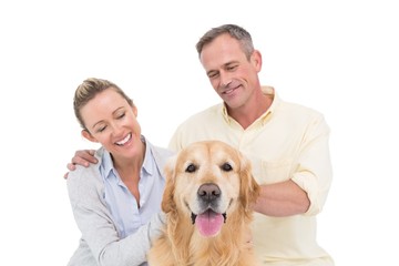 Smiling couple petting their golden retriever