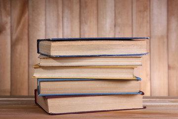 Books on wooden table on wooden wall background