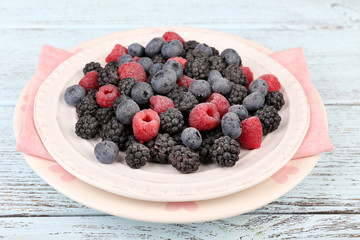 Iced berries on plate, on color wooden background