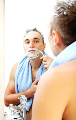 Obraz na płótnie Canvas Young man shaving his beard in bathroom