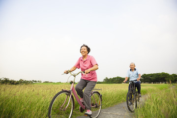 Fototapeta premium Happy Asian elderly seniors couple biking in the park with blue