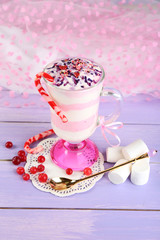 Cranberry milk dessert in glass, on color wooden background