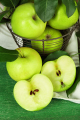 Ripe apples in metal basket with napkin on wooden background