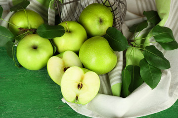Ripe apples in metal basket with napkin on wooden background