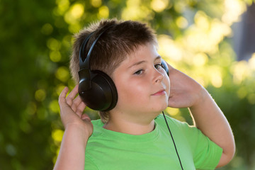 boy listening to music with headphones in  park