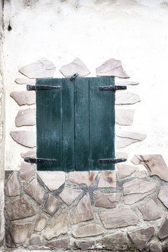 pared   de piedra con  ventana con postigos cerrados
