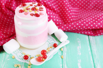 Raspberry milk dessert in glass jar, on color wooden background