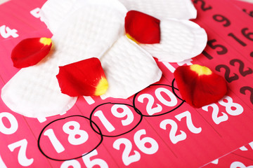 Sanitary pads and rose petals on calendar background