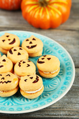 Tasty Halloween macaroons on plate, on wooden table