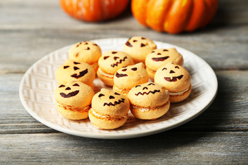 Tasty Halloween macaroons on plate, on wooden table