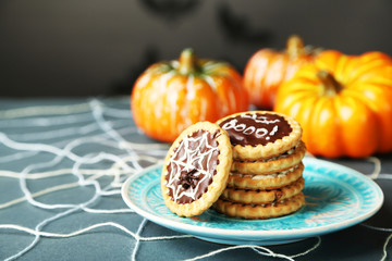Tasty Halloween cookies on plate, on decorative spiderweb