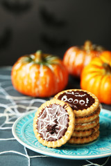 Tasty Halloween cookies on plate, on decorative spiderweb