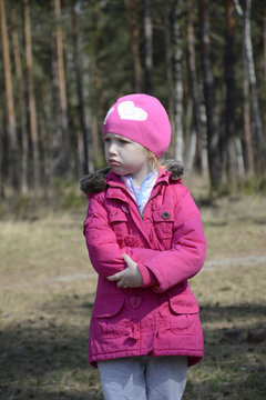 Little angry upset girl standing alone in the spring forest.