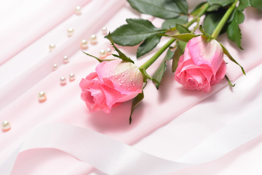 Pink rose flowers on pink cloth with pearls and ribbon