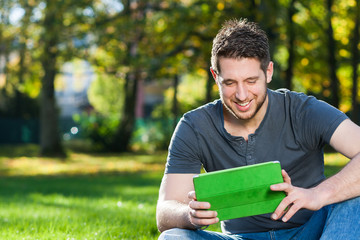 Mann mit Tablet PC im Park
