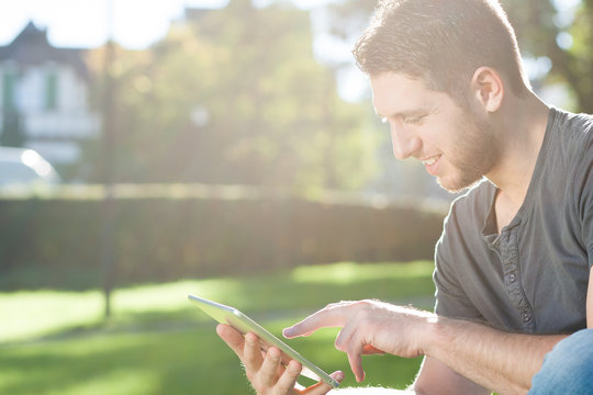 Junger Mann mit Tablet PC im Park