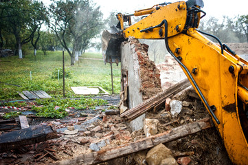 Excavator demolishing a concrete wall