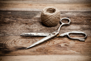 Old scissors and skein jute on wooden table