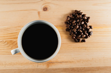 white cup of coffee on a wooden background and coffee beans