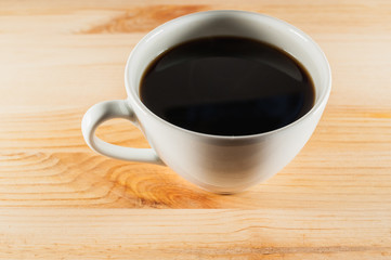 white cup of coffee on a wooden background