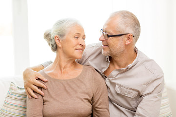 happy senior couple hugging on sofa at home