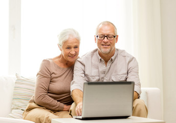 happy senior couple with laptop at home