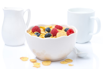 cornflakes with fresh berries in a bowl and milk, isolated