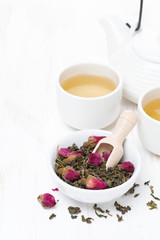 green tea with rosebuds, cups and teapot on white table