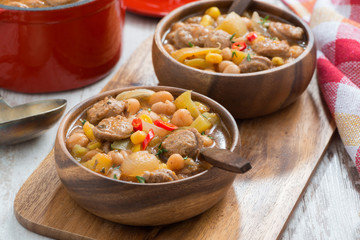 vegetable stew with sausages in a wooden bowl on board