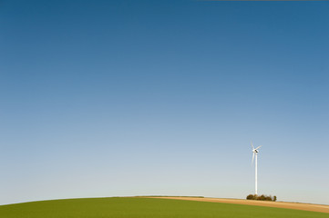 Ein Windkraftrad auf einem Hügel vor blauem Himmel