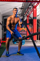 Fototapeta na wymiar battling ropes man at gym workout exercise