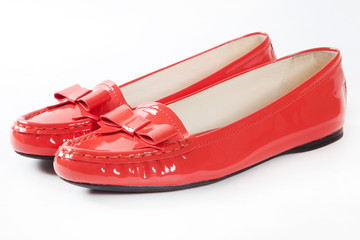 Female shiny red lack shoes with a bow isolated on white background
