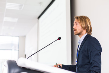 Handsome young man giving a speech at a conference