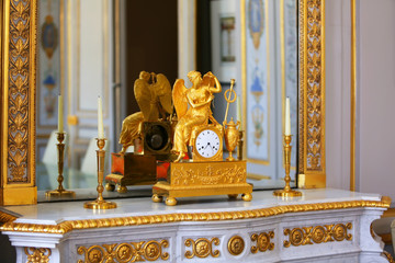 Antique clock with figurine of angel in vintage interior.